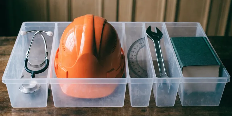 Compartmentalized tray containing tools: stethoscope, hard hat, protractor, wrench, notebook